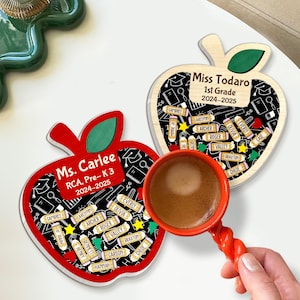 May include: Two apple-shaped wooden teacher gifts. One is red with "Ms. Carlee" and student names. The other is light wood with "Miss Todaro" and student names. A red coffee cup is in the image.