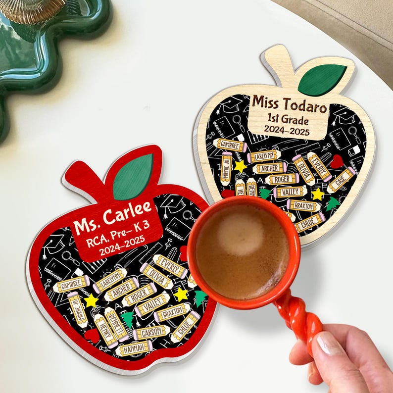 May include: Two apple-shaped wooden teacher gifts. One is red with "Ms. Carlee" and student names. The other is light wood with "Miss Todaro" and student names. A red coffee cup is in the image.