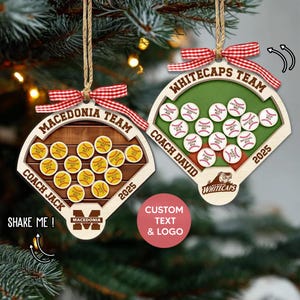 May include: Two baseball-themed Christmas ornaments. One features a wooden baseball diamond with the text "MACEDONIA TEAM" and "COACH JACK". The other says "WHITECAPS TEAM" and "COACH DAVID". Both have red and white checkered bows.