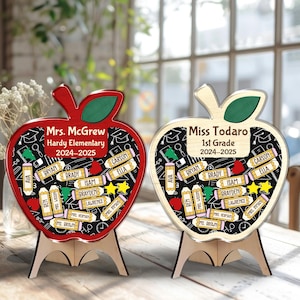 May include: Two apple-shaped wooden teacher appreciation gifts. One is red, the other is natural wood. Both have a black chalkboard design with student names and the text "Mrs. McGrew Hardy Elementary 2024-2025" and "Miss Todaro 1st Grade 2024-2025".