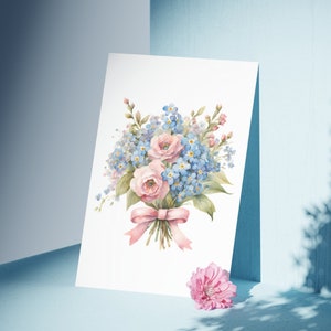 May include: A watercolor painting of a bouquet of pink and blue flowers tied with a pink ribbon. The flowers are arranged in a vase and the background is white.