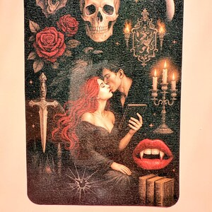 May include: A rectangular gothic-themed image featuring a skull, roses, a bat, and a kissing couple. Other elements include a sword, a candelabra, a broken glass effect, and vampire fangs. The colour palette is dark with red and gold accents.