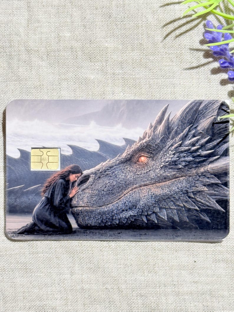 a debit card skin of a black dragon laying it's head down so a small woman may rest her head on his nose.
thestickerera