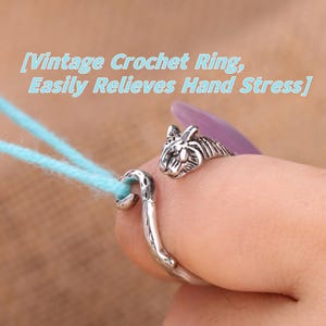 May include: A silver-toned crochet ring with a tiger head design. The ring is wrapped around a finger, with a hook-shaped end holding light blue yarn. Text on the image reads "Vintage Crochet Ring, Easily Relieves Hand Stress."