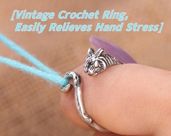 Peut inclure: Bague de crochet argentée avec une tête de tigre. La bague est portée sur un doigt, avec une extrémité en forme de crochet tenant du fil bleu clair. Le texte sur l'image indique : "Vintage Crochet Ring, Easily Relieves Hand Stress."