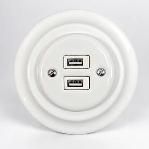 以下が含まれることがあります： 中央に垂直に積み重ねられた2つのUSBポートを備えた円形の白いウォールプレート。光沢のある白い表面は、中央のポートアセンブリの左右に配置された2本の銀色の金属製ネジで固定されています。