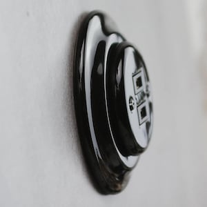 May include: A glossy black circular wall plate featuring a central dual-port data outlet. The fixture has a stepped, layered design with a smooth, reflective finish and two visible metal screws securing the central component to the outer base.