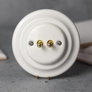 クラシックダブルトグルスイッチ – 2ギャング磁器製ライトスイッチ、EU Ø60 フラッシュマウント、フレーム付属、白または黒