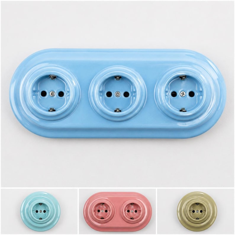 May include: A light blue triple electrical wall outlet with a glossy finish and a rounded rectangular base. Below, three additional outlets are shown: a single light blue outlet, a double pink outlet, and a single olive green outlet.