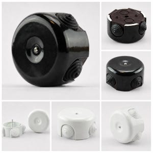 May include: A collage of electrical junction boxes in black, brown, and white. The boxes have a circular or hexagonal shape with multiple cable entry points. Some have a screw in the center. The boxes are made of plastic and have a glossy finish.