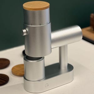 以下が含まれることがあります： 木製の蓋が付いた、銀色の手動コーヒーグラインダー。 グラインダーは、ハンドルとベースを備えた円筒形デザインです。 設定は数字でマークされています。 グラインダーは家庭での使用向けに設計されています。