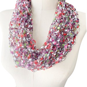 May include: A colorful crocheted infinity scarf with a mix of red, pink, green, white, and silver threads.