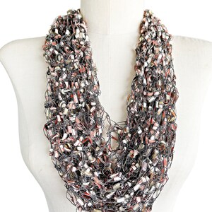 May include: A chunky knit scarf in shades of brown, cream, and silver. The scarf is made of a soft, lightweight yarn and is perfect for adding a touch of warmth and style to any outfit.