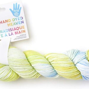 May include: A skein of hand-dyed yarn in shades of blue, green, and yellow. The yarn is labeled "Hand Dyed Heaven Laine Paradisiaque Teinte a la Main".