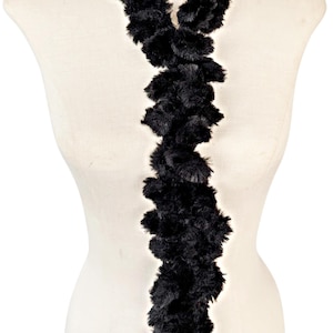 May include: A long black faux fur scarf with a ruffled texture.