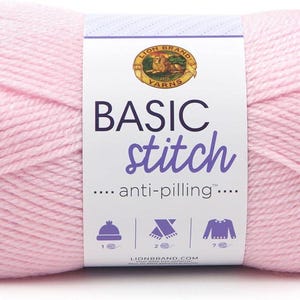 May include: A large ball of light pink yarn with a label that reads "BASIC stitch anti-pilling." The label features a logo and icons of a hat, scarf, and sweater. This yarn is suitable for knitting and crochet projects.