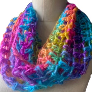 May include: A rainbow colored crocheted infinity scarf. The scarf is made with a chunky yarn and has a loose, open weave.