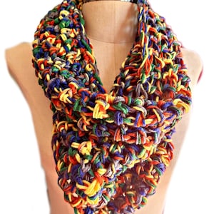 Puede incluir: Bufanda infinita hecha a mano, exhibida en un maniquí. Presenta una mezcla de colores vibrantes: rojo, amarillo, azul, verde y gris. El diseño de punto grueso añade textura e interés visual, ideal para añadir un toque de color a cualquier atuendo.