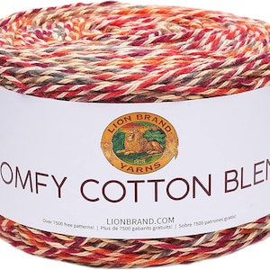 May include: A skein of Lion Brand Comfy Cotton Blend yarn in a multi-colored pattern of red, orange, brown, and cream. The label reads "Lion Brand Yarns 1878 Comfy Cotton Blend" and "LionBrand.com Over 7500 free patterns! Plus de 7500 gabarits gratuits! / Sobre 7500 patrones gratis!"