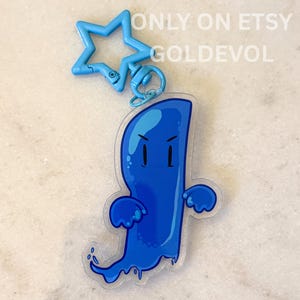 Puede incluir: Un llavero de acrílico azul con un personaje de fantasma de dibujos animados con expresión severa, unido a un cierre de plástico azul claro en forma de estrella. El texto ONLY ON ETSY GOLDEVOL está impreso en color blanco.