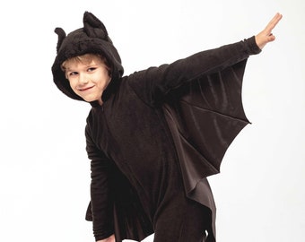 May include: A black bat costume with attached wings and a hood with bat ears. The costume is a one-piece jumpsuit with long sleeves and legs. The word "Sashka" is printed on the lower right side of the costume.