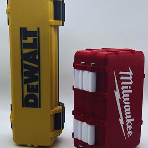 Könnte beinhalten: Zwei Werkzeugkästen, einer gelb mit dem Wort "DEWALT" darauf und einer rot mit dem Wort "Milwaukee" darauf.