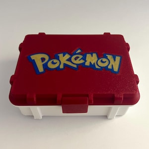 May include: A red and white plastic Pokemon trading card storage box with the Pokemon logo on the lid.