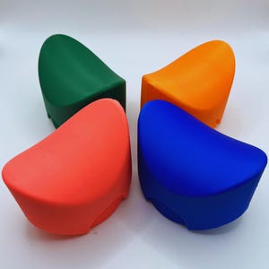 K&ouml;nnte beinhalten: Vier farbenfrohe K&uuml;chenhelfer aus Silikon in Gr&uuml;n, Orange, Rot und Blau. Jedes hat eine gew&ouml;lbte Oberseite und eine geriffelte Unterseite. Die Objekte sind quadratisch vor einem wei&szlig;en Hintergrund angeordnet.