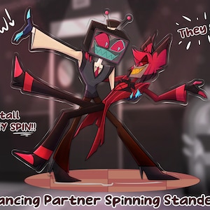 May include: A cartoon illustration of two characters dancing on a stage. One character has a TV for a head, the other is red with horns. Text reads "Wow!" and "They spin!" The standee is 6 inches tall.