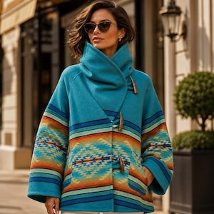 Könnte beinhalten: Ein petrolfarbener Wollmantel mit hohem Kragen und Knebelverschlüssen. Das Kleidungsstück zeigt ein horizontales geometrisches Muster in Orange-, Blau- und Cremetönen im Mittelteil und an den Ärmeln, mit weiten Ärmeln und einer strukturierten Silhouette.