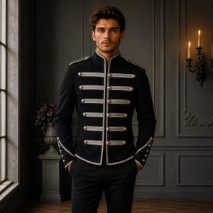 May include: A black military-style jacket featuring a high collar, long sleeves, and silver-toned metallic buttons arranged in horizontal rows across the front. The garment includes silver piping trim along the edges and cuffs, creating a structured look.