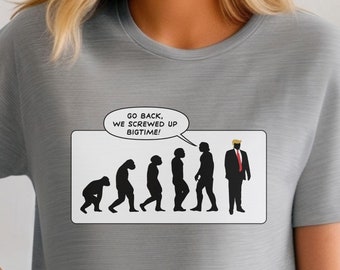 May include: A gray t-shirt with a white graphic of a cartoon evolution chain ending with a caricature of Donald Trump. The graphic includes a speech bubble with the text "Go back, we screwed up bigtime!"