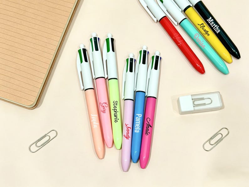 May include: A collection of multi-color ballpoint pens featuring white clips and barrels in various pastel and vibrant colors. Each pen is personalized with a name printed in script or print font, including Linda, Gary, Stephanie, Sandy, Pamela, Annie, Ashley, Denise, Marilyn, and Martha.