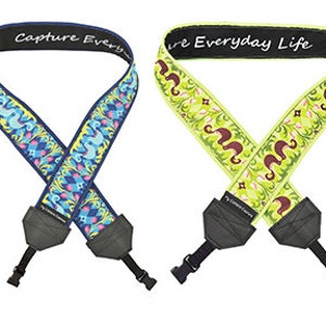May include: Two camera straps with colorful patterned designs. The strap on the left is blue and green with a floral pattern and the text "Capture Every Moment". The strap on the right is yellow and green with a floral pattern and the text "Everyday Life".