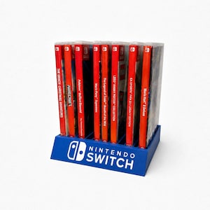 Op de afbeelding: Een blauwe plastic Nintendo Switch-spelhouder met acht videospelhoesjes. De houder is aan de voorzijde voorzien van het witte Nintendo Switch-logo en de tekst. De speltitels zijn onder andere The Grinch, Minecraft, Pokémon Brilliant Diamond, Mario Party Superstars, The Legend of Zelda: Breath of the Wild, LEGO Harry Potter Collection, EA Sports FIFA 23 en Mario Kart 8 Deluxe.