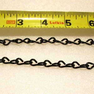 May include: Black chain with heart-shaped links, measured with a yellow tape measure. The chain is approximately 5 inches long.