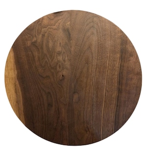 Könnte beinhalten: Ein runder Holzschneidebrett mit einer satten, dunkelbraunen Farbe und sichtbaren Holzmaserungsmustern. Das Brett ist kreisförmig und scheint aus einem einzigen Holzstück gefertigt zu sein, das natürliche Variationen aufweist.