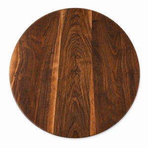 May include: A circular wooden tabletop featuring a rich, dark brown grain pattern with visible vertical wood striations and natural color variations throughout the surface, presented from a direct top-down perspective against a plain white background.