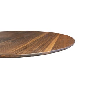May include: A close-up of a round, wooden table top. The surface is a rich brown color with a natural wood grain pattern. The edge of the table is visible, showing the thickness and shape.