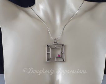 Colgante geométrico de plata de ley con detalles de rubí: joyería inspirada en el arte moderno