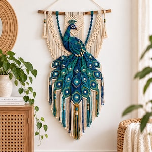 Peut inclure: Une tenture murale en macramé représentant un paon dans des tons bleu sarcelle, bleu et crème. Le paon est réalisé avec des cordons noués complexes, agrémenté de perles en bois et suspendu à une branche en bois naturel avec des franges.