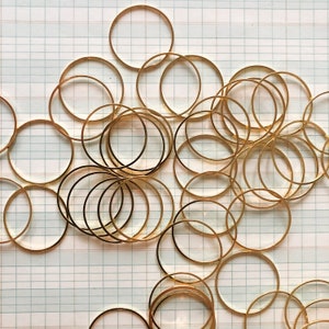 May include: A large group of gold-colored metal rings, stacked and overlapping, creating a circular pattern. The rings are all the same size and shape, and they are arranged in a random order.