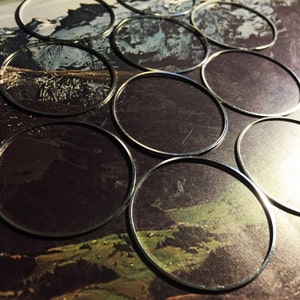 May include: A close-up of a set of silver-colored metal hoops, arranged in a circular pattern on a background of a landscape image. The hoops are all the same size and are arranged in a way that creates a sense of depth and dimension.