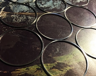 May include: A close-up of a set of silver-colored metal hoops, arranged in a circular pattern on a background of a landscape image. The hoops are all the same size and are arranged in a way that creates a sense of depth and dimension.