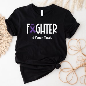 May include: Black t-shirt with a white graphic that says "FIGHTER" with a purple ribbon and the text "#Your Text" underneath.
