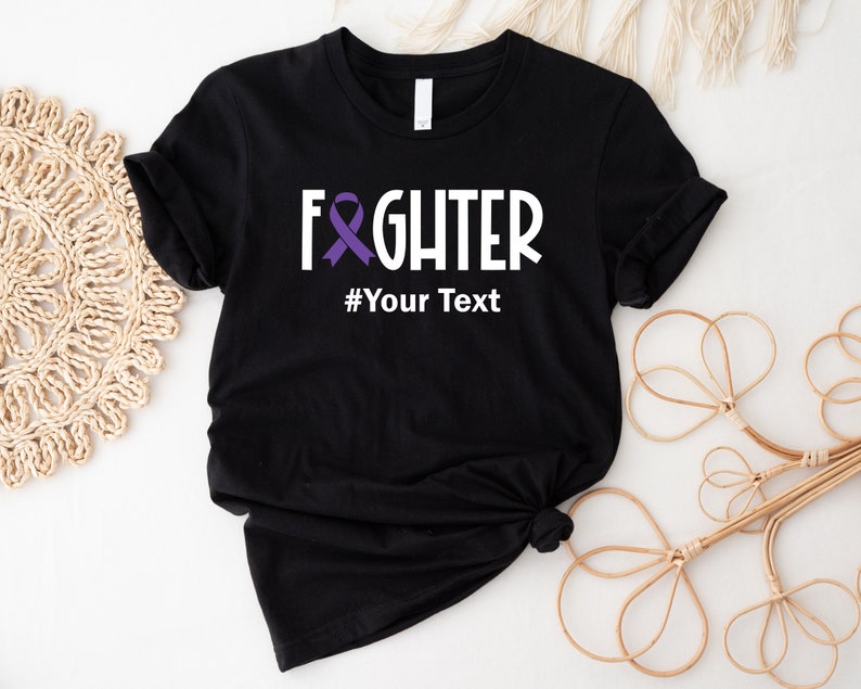May include: Black t-shirt with a white graphic that says "FIGHTER" with a purple ribbon and the text "#Your Text" underneath.