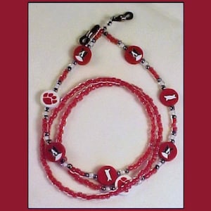 May include: Red and white beaded eyeglass chain with paw print and dog charms.