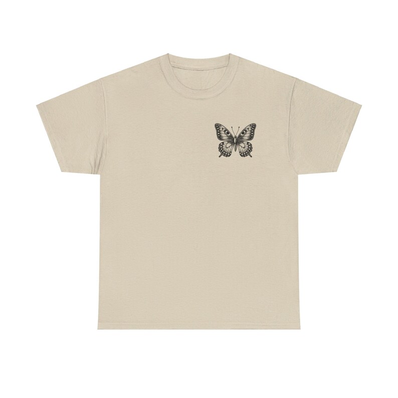 May include: A beige t-shirt with a black butterfly graphic on the left chest.