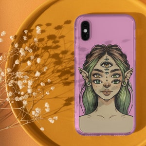 Op de afbeelding: Een roze telefoonhoesje met een afbeelding van een vrouw met meerdere ogen en elfenoren. De vrouw heeft groen haar en draagt een roze top.