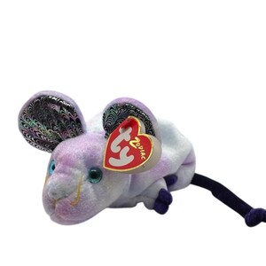 May include: A plush toy mouse in shades of lavender and white, featuring iridescent ears and teal eyes. The mouse has a long, dark blue tail and a red heart-shaped tag that reads "ZODIAC".